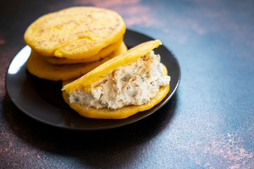 Latin American breakfast Arepas (arepa) of ground maize dough with cheese and herbs. Cuisine of Venezuela and Colombia. Close-up view, dark background, copy space