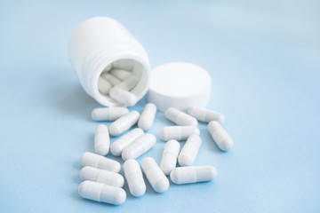 prescription opioids spilling from white bottle with copy space. on a blue background
