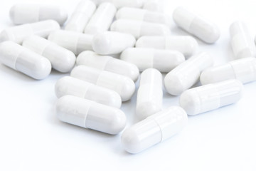 Several white capsules of drugs and pills on a white isolated background.