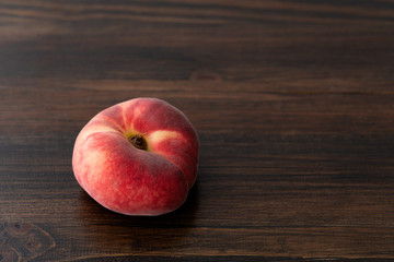 Fresh organic saturn peaches on a dark wooden table