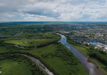Fototapeta na wymiar Irbit city and river. Russia. Aerial. Summer, cloudy. A lots of trees and grass