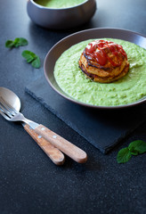 Traditional Australian dish called Pie Floater. Green pea soup served with Australian meat pie. Australian cuisine. Black background. Close-up. Copy space