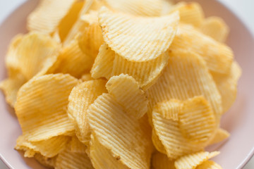Heap of ribbed potato crisps. Potato chips, unhealthy eatting.