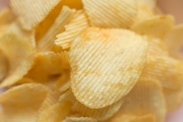 Heap of ribbed potato crisps. Potato chips, unhealthy eatting.