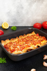 Mexican Enchiladas with chicken, vegetables, corn, beans and cheese. Served in a baking tray on a black table. Mexican food. Latin American cuisine. Gray background, close up, copy space
