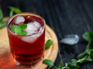 Red alcoholic cocktail with ice and mint in a glass