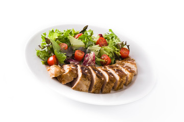 Grilled chicken breast with vegetables on a plate isolated on white background