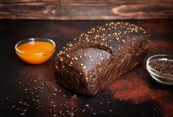 Whole grain rye bread, honey and malt on a dark wooden background. Freshly baked homemade bread. Close-up, selective focus