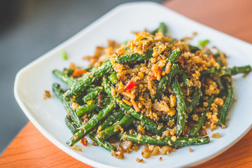 stir fried long beans with chilli and salted fish served on a  white plate