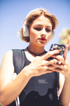 Lifestyle Photography. A blonde young girl  with an electronic device in a sunny day in summer.