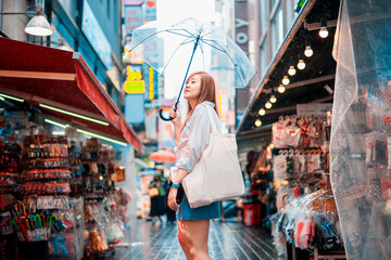 Fototapeta na wymiar spring and raining season activity concept from beauty asian woman travel and shopping with hold her umbrella with city and street food market background