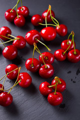 Cherries on a slate board. Sweet cherries on a dark background. Red berries in drops of water on black boards. Healthy food. Top view. Copy space