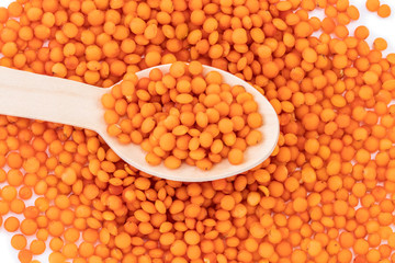 red lentils on wooden spoon isolated on white background