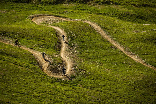 Mountain Bikers riding a singletrack with berms in the Bike Park and Les Deux Alpes, France.