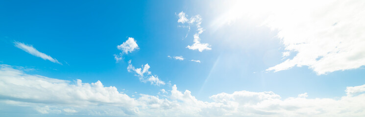 Sun shining over a blue sky with white clouds