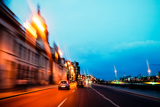 Driving at dusk through the streets of Dublin City, Ireland. Speed blur of orange lights and blue sky