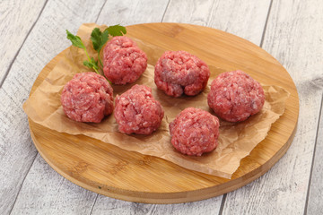 Raw meatball over wooden background