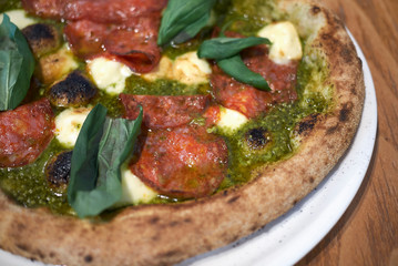 Pizza with salami, pesto and basil