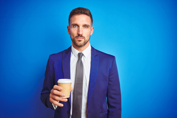 Young handsome business man drinking a coffee on a paper cup over blue isolated background with a confident expression on smart face thinking serious
