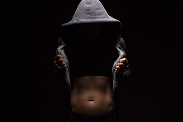 Woman with perfect body opens her hoodie and shows her trained abdominal muscles. Fitness, workout and training concept.