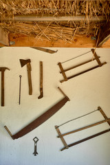 Tools on the wall of the hut. Hammer, saw, metal and wood