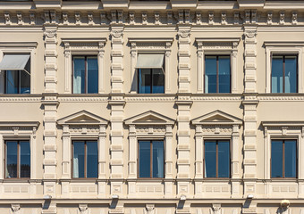 Fragment of the facade of the historic city building. Windows with cornices and decor..