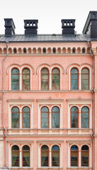 Fototapeta na wymiar A fragment of the facade of a beautiful pink city building. Windows with a semicircular part