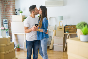 Young couple moving to a new house, using smartphone smiling very happy for new apartment