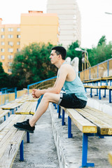 A young man sitting on a bench and tying his shoelaces in the fresh air