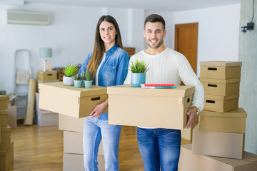 Fototapeta na wymiar Young couple moving to a new home, smiling happy holding cardboard boxes at new apartment
