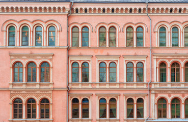 Fototapeta na wymiar The facade of a beautiful pink city building. Windows with semicircular part.