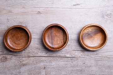 From above view of three brown wooden bowls on gray wooden table. Traditional rustic bowl.