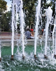 In the foreground is a photo of a fountain with spouting cascades of water, and through a spray of water you can see a couple in love where a guy hugs a girl.
