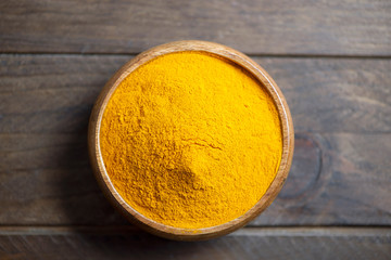 From abowe bowl with curcumin powder on brown wooden table. Spice for health and ingredient of...
