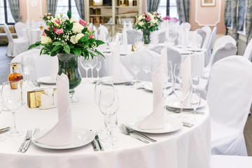Wedding. Banquet. Round table for guests, served with cutlery, flowers and crockery and covered with a tablecloth