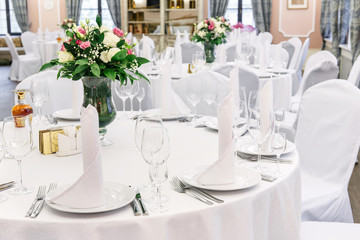 Wedding. Banquet. Round table for guests, served with cutlery, flowers and crockery and covered...