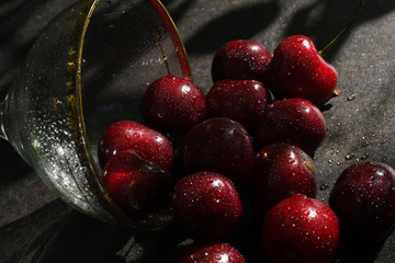 Large glass of ripe cherries in drops of water ,dark background.selective focus. Macro.Copy space
