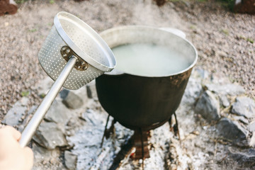 Cooking at the camp fire traditional dish. The process of cooking dumplings with a help of colander..