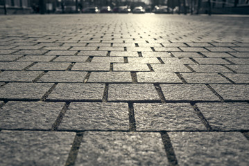 Paving tiles background. Paving slabs close-up on the background of cars in the blur.