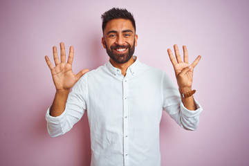 Naklejka premium Young indian businessman wearing elegant shirt standing over isolated pink background showing and pointing up with fingers number nine while smiling confident and happy.