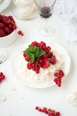 Pavlova fruit cake with strawberry, raspberry, red currant and mint leaves on white background. Selective focus. Healthy food concept