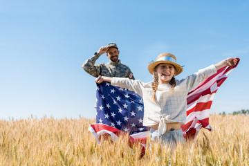 selective focus of cheerful child standing with american flag near soldier