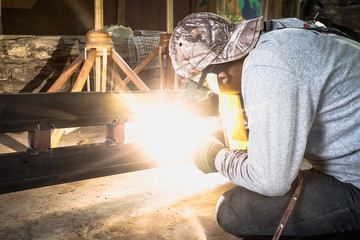 Industrial Worker at the factory welding closeup. Electric wheel grinding on steel structure in factory.