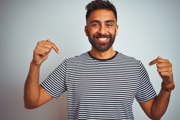 Young indian man wearing black striped t-shirt standing over isolated white background looking...