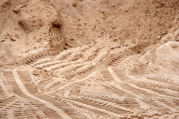 Traces of tread construction equipment on the sand. Background in blur.