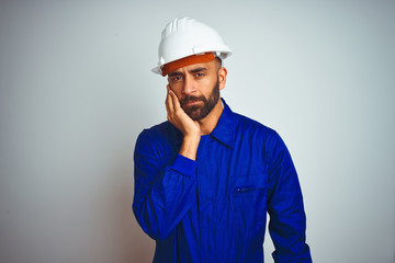 Handsome indian worker man wearing uniform and helmet over isolated white background thinking looking tired and bored with depression problems with crossed arms.