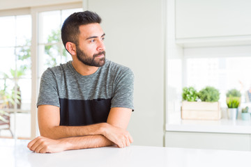Handsome hispanic man wearing casual t-shirt at home looking to side, relax profile pose with natural face with confident smile.