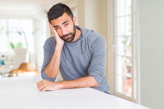 Handsome hispanic man wearing casual sweatshirt at home thinking looking tired and bored with depression problems with crossed arms.