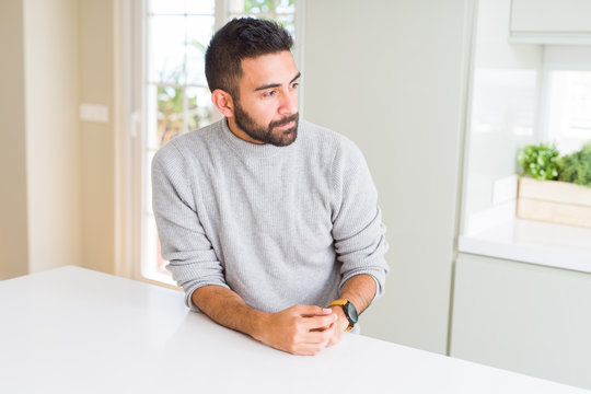 Handsome hispanic man wearing casual sweater at home looking to side, relax profile pose with natural face with confident smile.