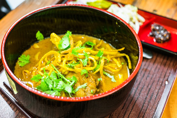 Angle view of Thai curried noodle soup with chicken with ingredients. Thai travel and street food.